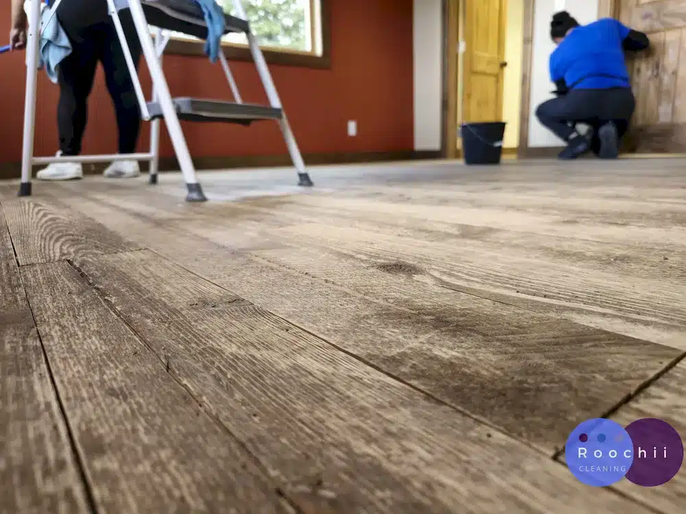 Roochii Cleaning team professionally cleaning a wooden house, captured from a floor-level angle showcasing the polished wooden flooring in Thornton Co