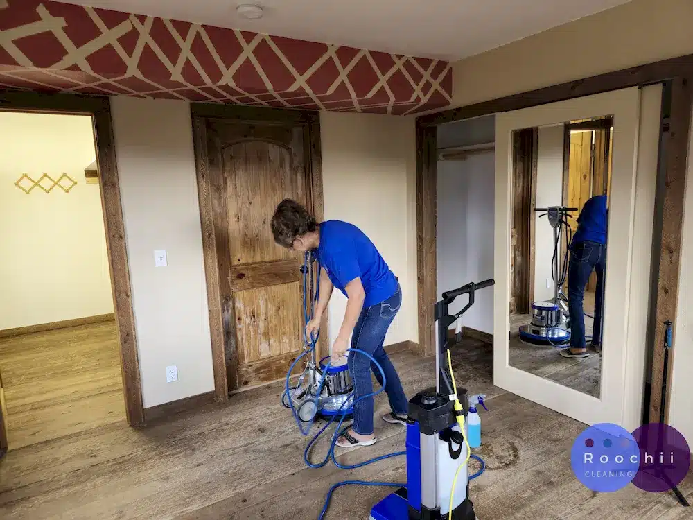 Roochii Cleaning team vacuuming water residue after polishing a wooden floor, captured from a high-angle perspective in Thornton Co