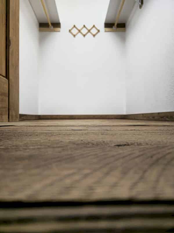 Roochii Cleaning professional cleaning a hallway in University, sweeping dust and debris from dark wooden floors.