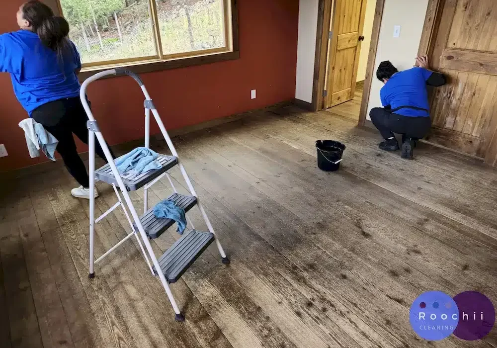 Roochii Cleaning team performing professional move-out cleaning services, meticulously scrubbing baseboards and window sills in a room for a perfect clean