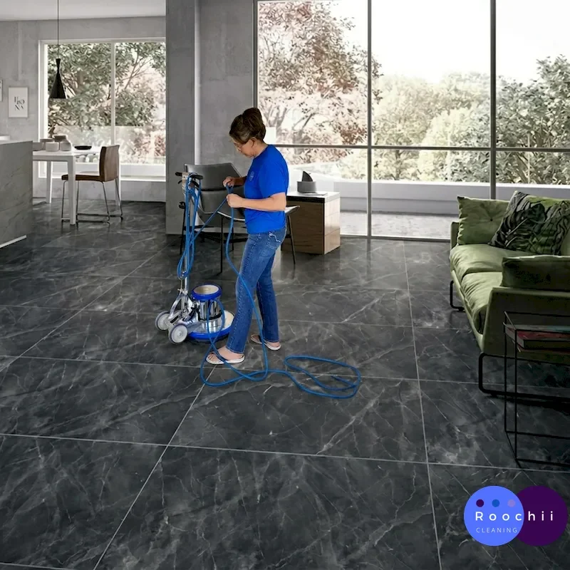 Cleaning technician in blue shirt manages blue cord while operating a floor polisher in a modern Colorado home.